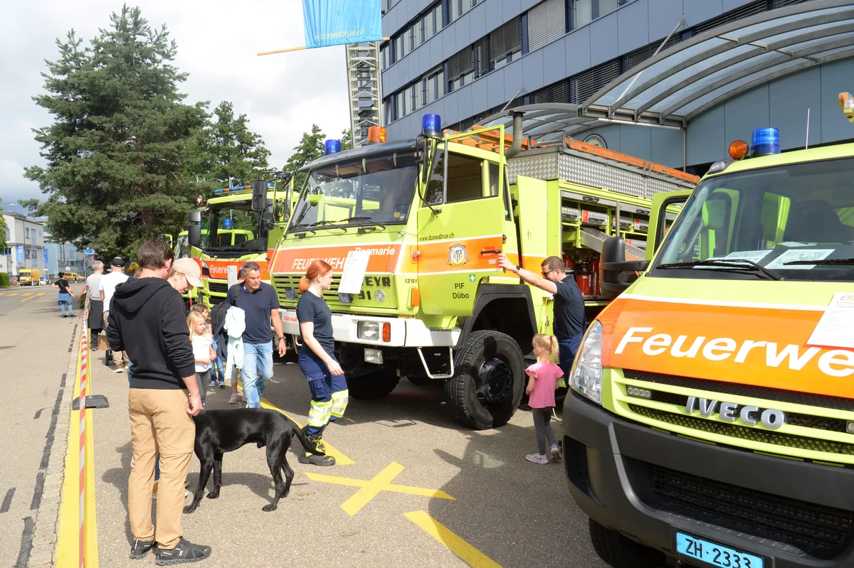Mehrere Personen begutachten Feuerwehrautos. 